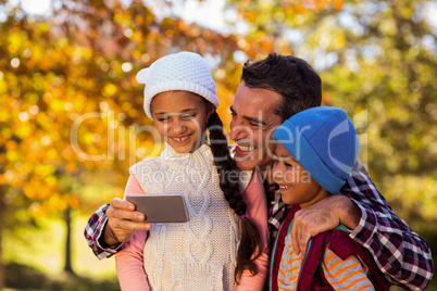 Happy father with children looking at mobile phone at park