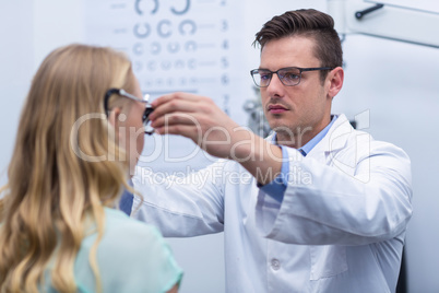 Optometrist examining female patient with phoropter