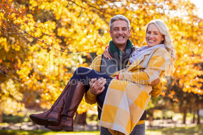 Portrait of happy man carrying woman at park