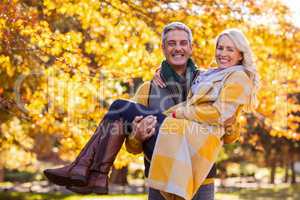 Portrait of happy man carrying woman at park