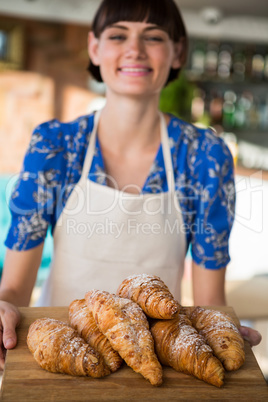 Smiling waitress holding a tray of croissants