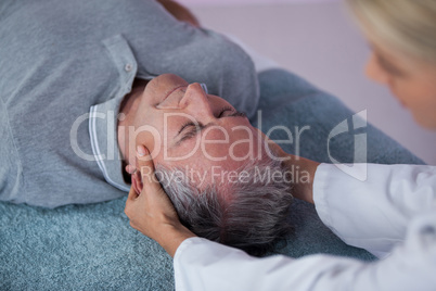 Senior man receiving neck massage from physiotherapist