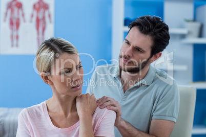 Physiotherapist massaging shoulder of a female patient