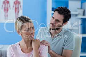 Physiotherapist massaging shoulder of a female patient