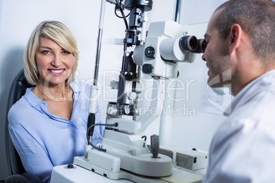 Optometrist examining female patient on slit lamp