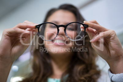 Female customer holding spectacles in optical store