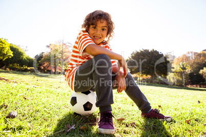 Portrait of smiling boy sitting on soccer ball