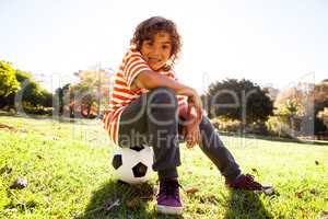 Portrait of smiling boy sitting on soccer ball