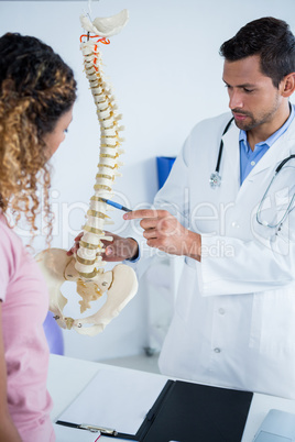 Physiotherapist explaining spine model to patient