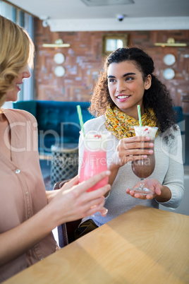 Female friends having milkshake in cafeteria