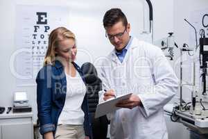 Optometrist discussing eye test report with female patient