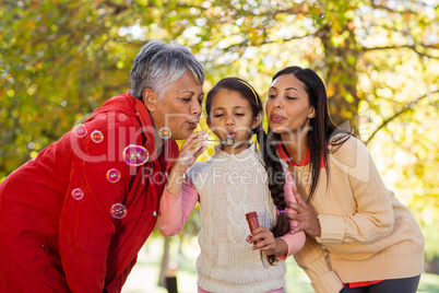 Daughter with mother and grandmother blowing bubbles