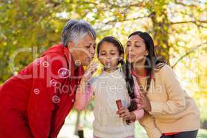 Daughter with mother and grandmother blowing bubbles