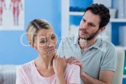 Physiotherapist massaging shoulder of a female patient