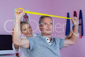 Senior man training with exercise band assisted by physiotherapi