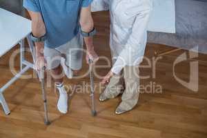 Physiotherapist helping patient to walk with crutches
