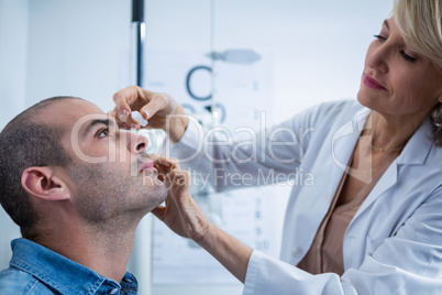 Optometrist putting drops into patients eyes