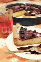 Piece of pie with bilberry on the plate and cup of tea