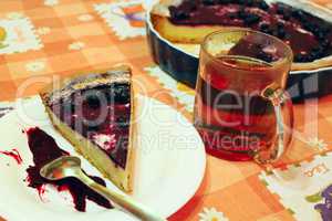 Piece of pie with bilberry on the plate and cup of tea