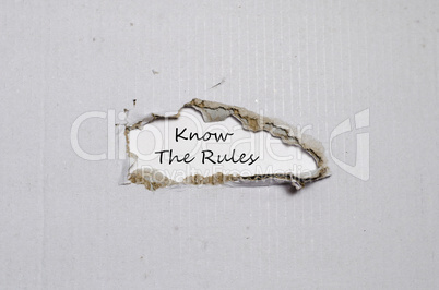The words know the rules appearing behind torn paper