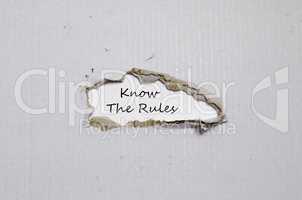 The words know the rules appearing behind torn paper