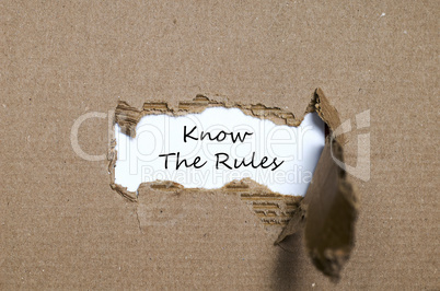 The words know the rules appearing behind torn paper