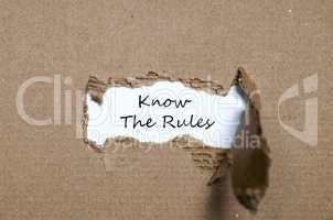 The words know the rules appearing behind torn paper