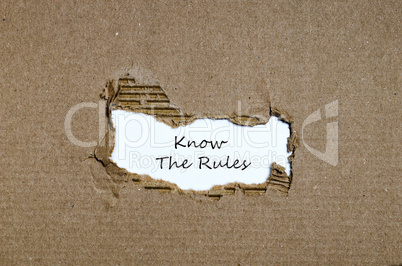 The words know the rules appearing behind torn paper