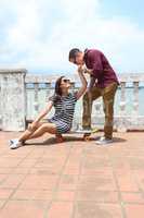 Young woman sitting on skateboard with boyfriend kissing forehea