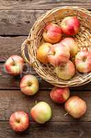 Fresh red apples in wicker basket on wooden table.