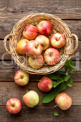 Fresh red apples in wicker basket on wooden table.