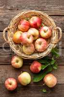 Fresh red apples in wicker basket on wooden table.