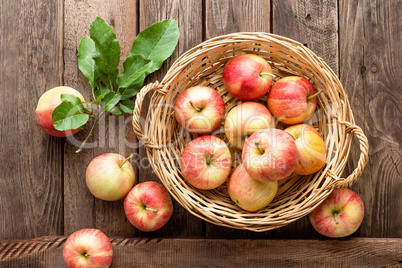 Fresh red apples in wicker basket on wooden table.