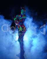 Girl with body art poses in UV light and smoke