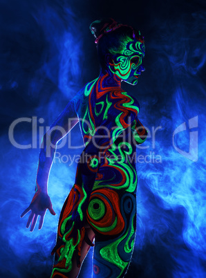 Rear view of naked girl with body art in UV light