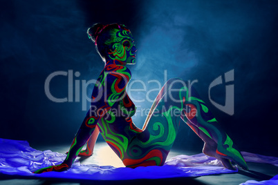 Girl with body art glowing under ultraviolet light