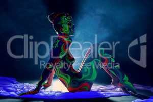 Girl with body art glowing under ultraviolet light