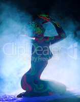 Side view of nude girl with body art in smoke