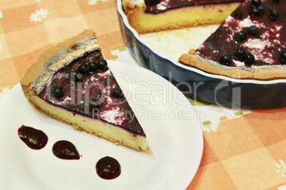 Piece of pie with bilberry on the plate and cup of tea