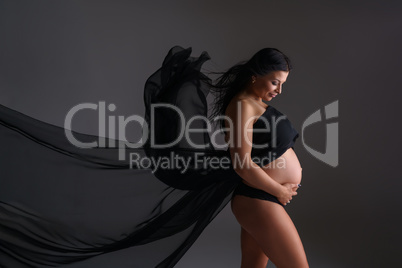 Elegant expectant mother poses with flying cloth