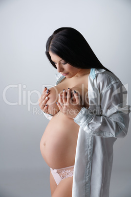 Femininity. Beautiful pregnant woman poses topless