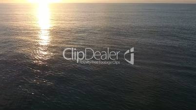 flying drone shot of a sea surface with a beautiful sunset