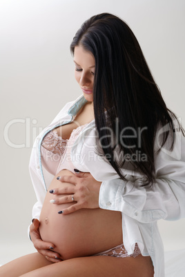 Dark-haired pregnant woman posing in studio
