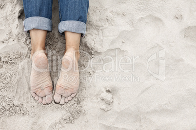 Sandy young woman feet on the beach