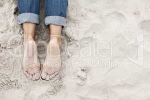 Sandy young woman feet on the beach