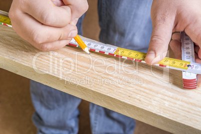 Carpenters hands with pencil and measuring tape