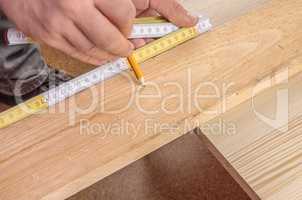 Carpenter's hands measuring a wooden board