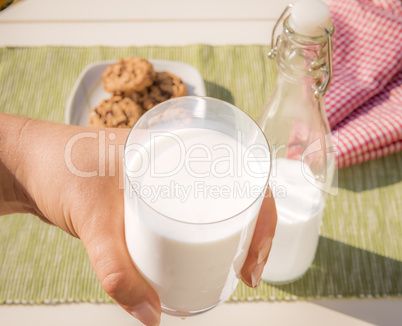 Glass of milk held in hand .