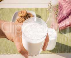 Glass of milk held in hand .