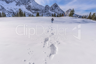 Man walking through snow on a mountain peak
